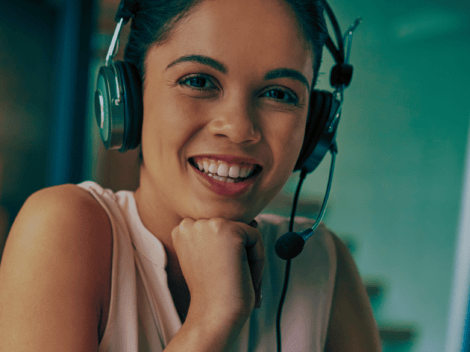 Female wearing a headset and smiling while she's on-call.